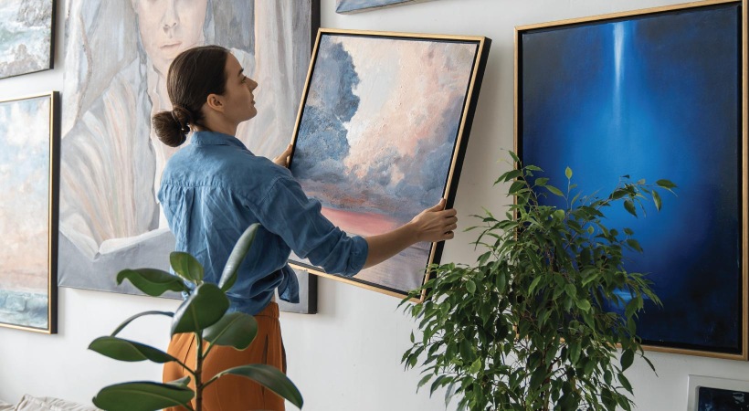 a person hanging a painting on a wall